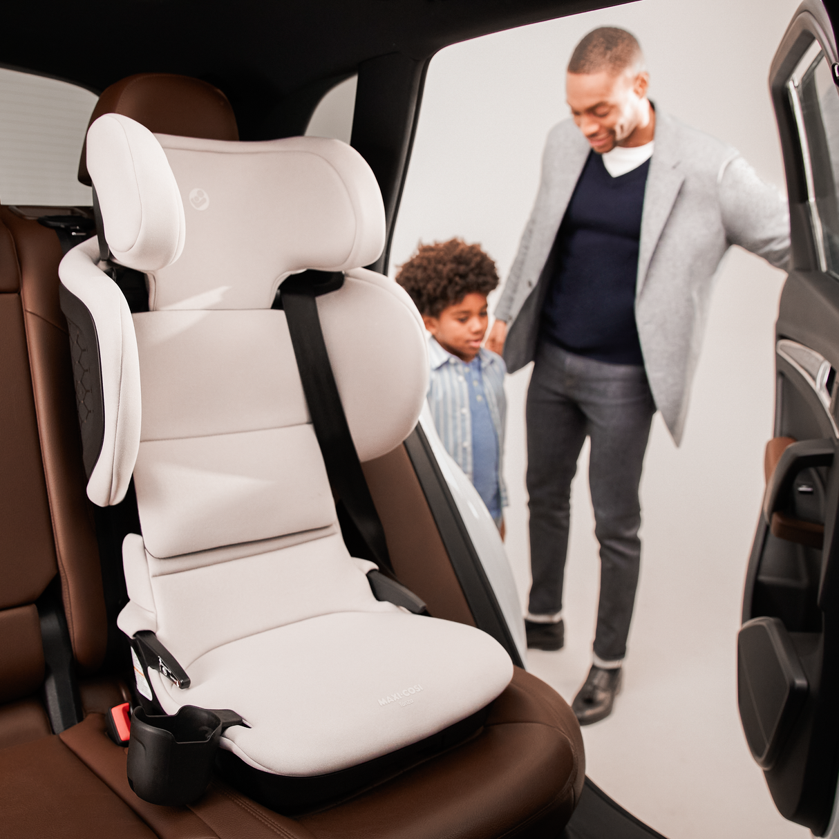 Child safety seat in a car with a man and child in the background