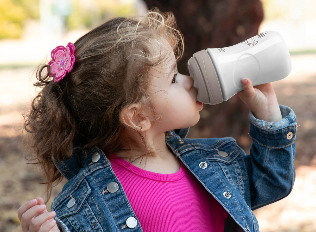 Child drinking from a white cup outdoors