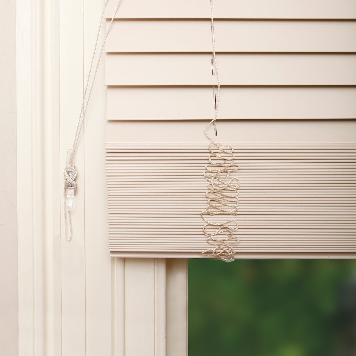 Window with beige blinds and a green outdoor view