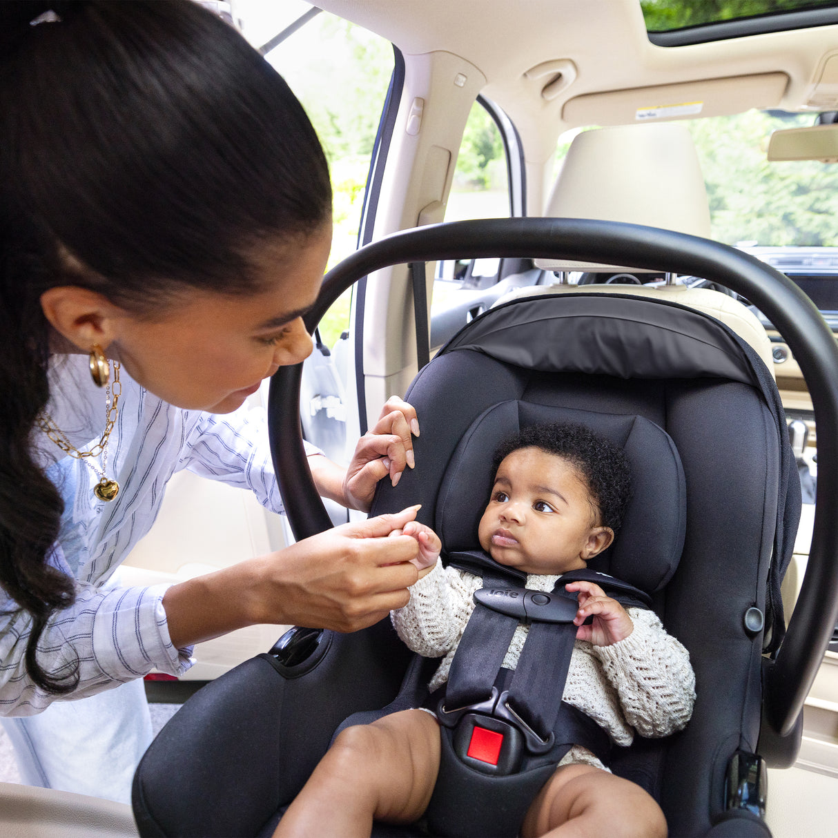 Woman securing a child in a car seat inside a vehicle