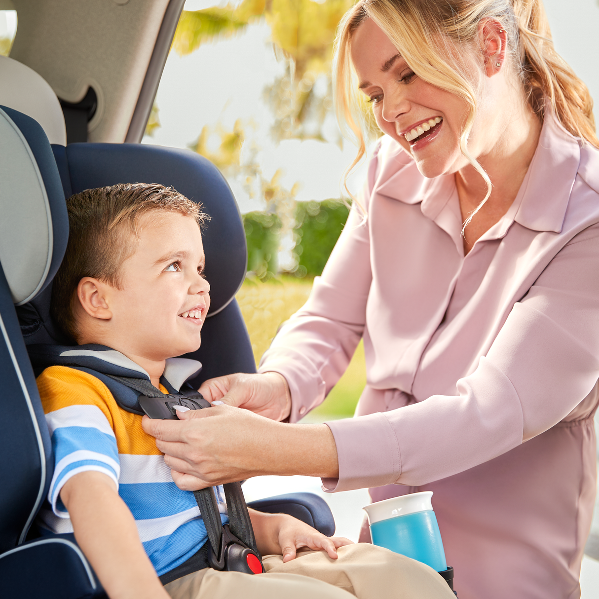 Woman securing a child in a car seat outdoors