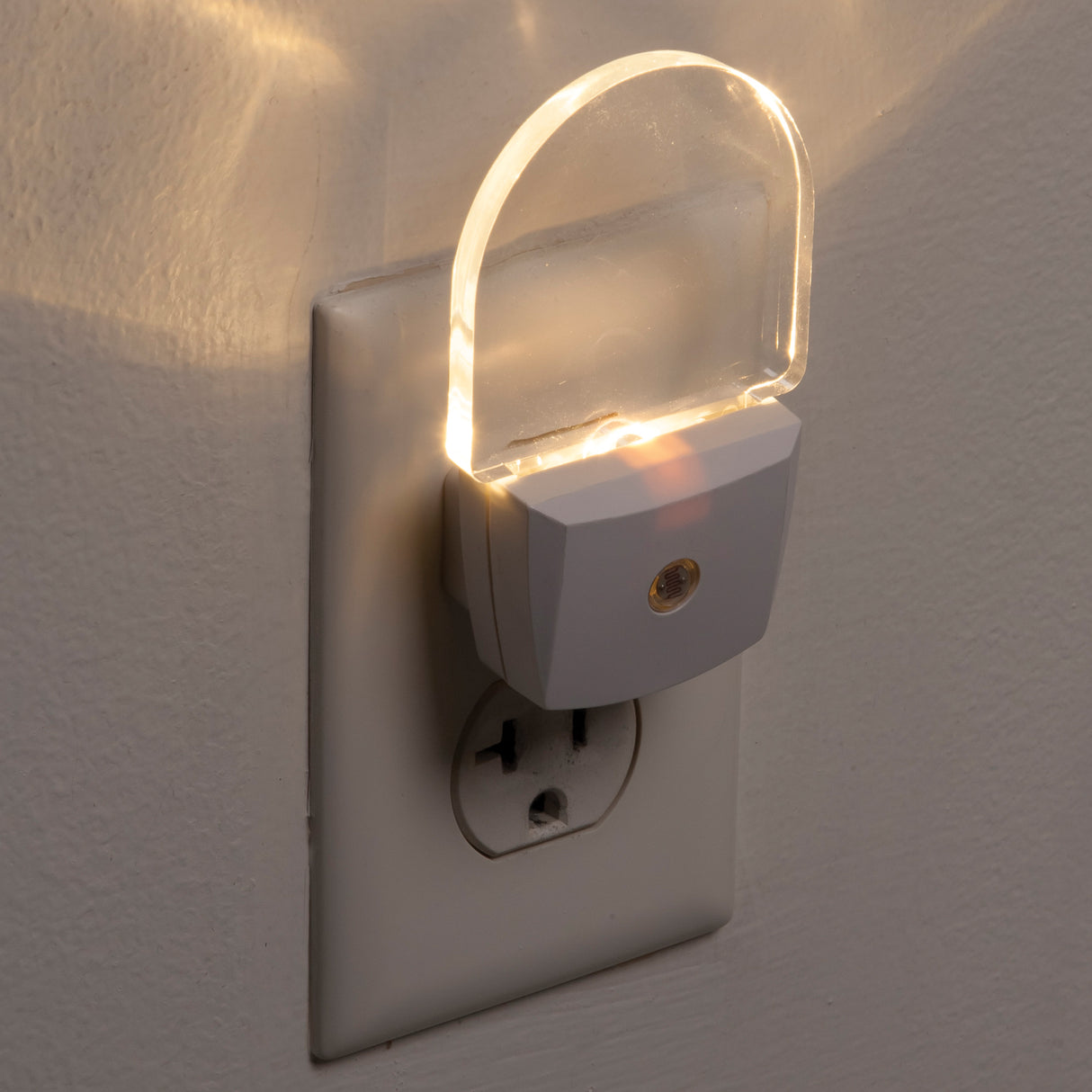 Plug-in night light emitting a warm glow on a wall socket.