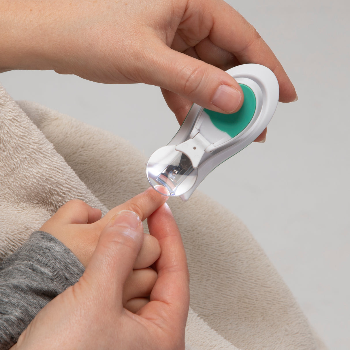 a mother using baby nail clippers to clip a baby's nails