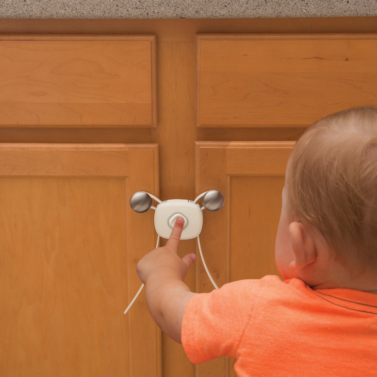 Child interacting with a safety lock on a wooden cabinet door