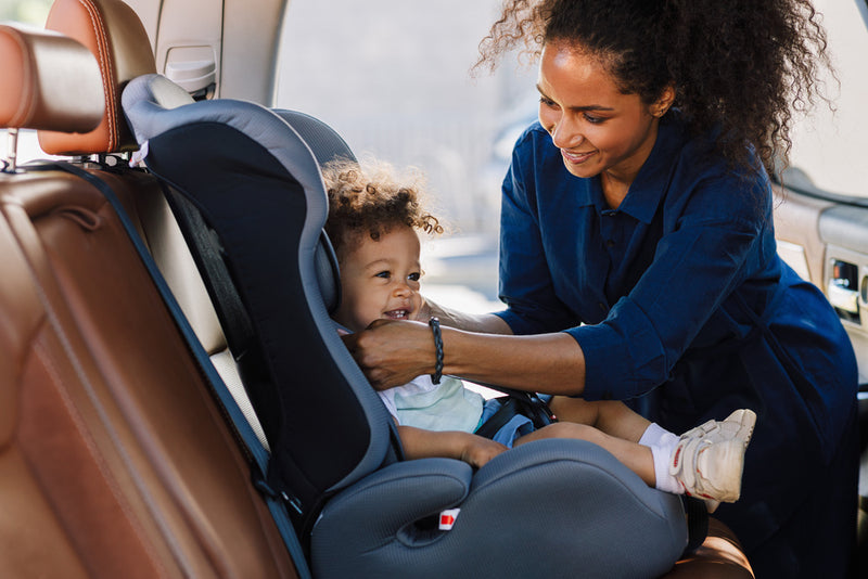 Woman adjusting a child in a car seat inside a vehicle