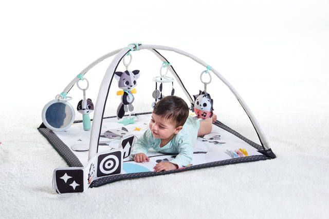 Baby enjoying tummy time on an infant play mat with hanging sensory toys, mirror, and high-contrast designs for early development and visual stimulation.