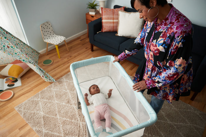 Woman interacting with a baby in a crib in a living room setting