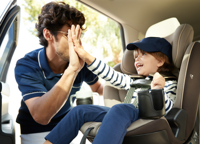 Man and child in a car seat giving each other a high-five.
