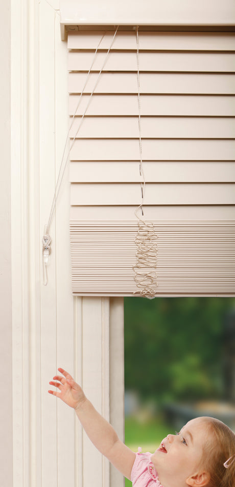 Child reaching out to touch a window blind with a blurred outdoor background