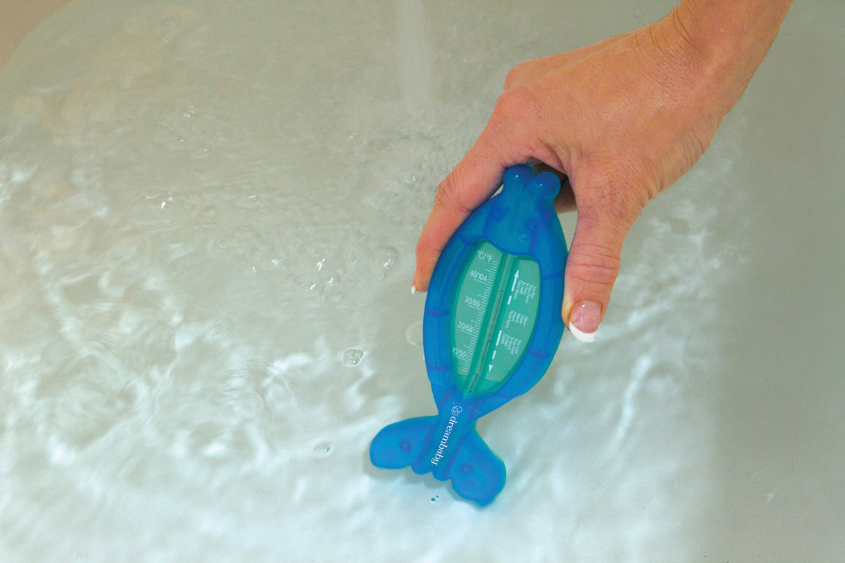 Hand holding a blue fish-shaped water tester in water