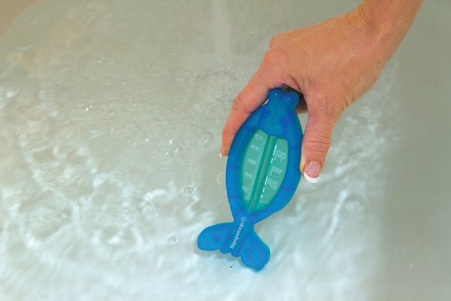 Hand holding a blue fish-shaped water tester in water