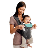 Woman holding a baby in a gray and teal baby carrier against a white background
