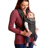 Woman holding a baby in a carrier against a white background