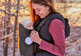 Woman carrying a baby in a carrier outdoors during winter