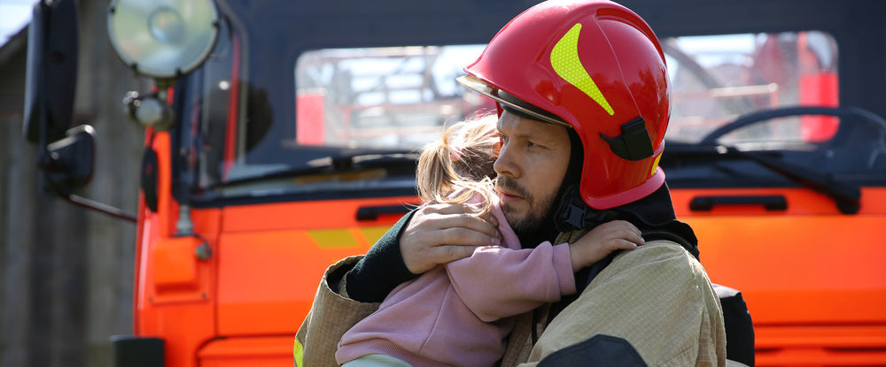 Firefighter holding a child in front of a fire truck