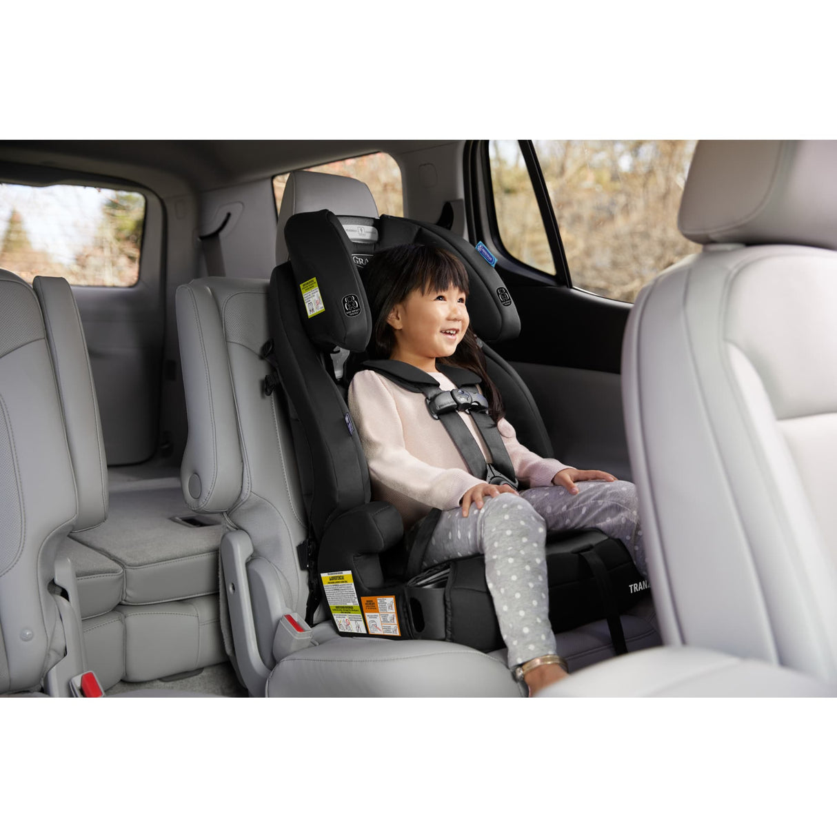 Child in a car seat inside a vehicle with a blurred outdoor background