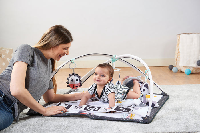 Woman and baby playing on a baby play mat with toys