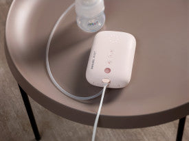 White electronic device on a round brown table with a clear bottle in the background
