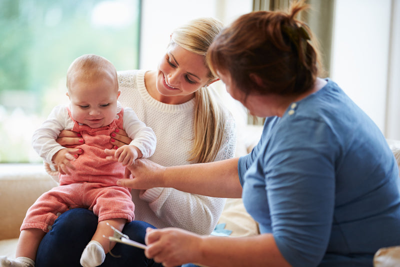 Woman holding a baby while another woman examines the baby's foot