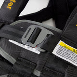 Close-up of a black harness with a buckle and safety label on a white background