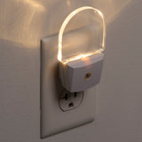 Plug-in night light emitting a warm glow on a wall socket.