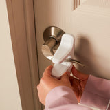 Person using a white door handle cover on a doorknob.