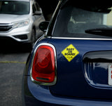 Car with a 'Baby on Board' sign on the back, parked in a lot.