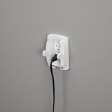 White electrical outlet with a black cord plugged in on a gray wall