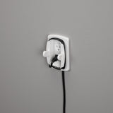 Wall-mounted electrical outlet with a black cord plugged into it on a gray background