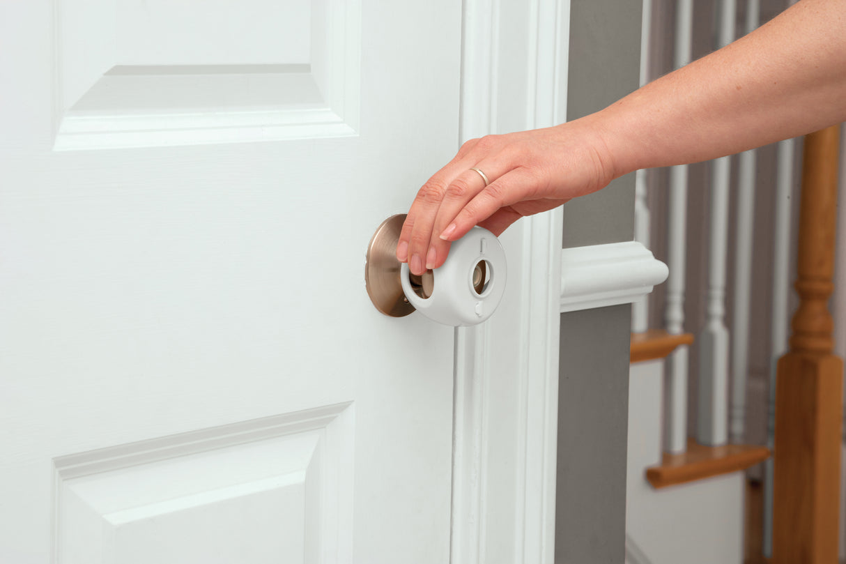 Hand opening a white door with a wooden handle
