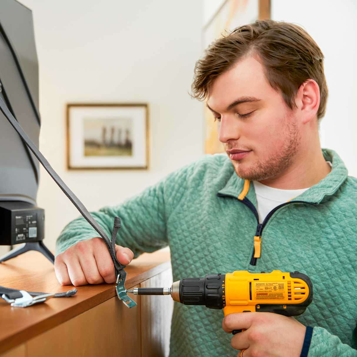 Man using a drill on a piece of furniture indoors