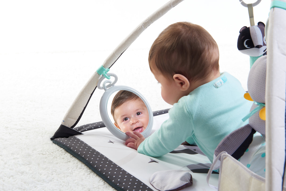 Baby playing on an infant play mat with a hanging mirror toy, promoting self-recognition, tummy time, and sensory development.